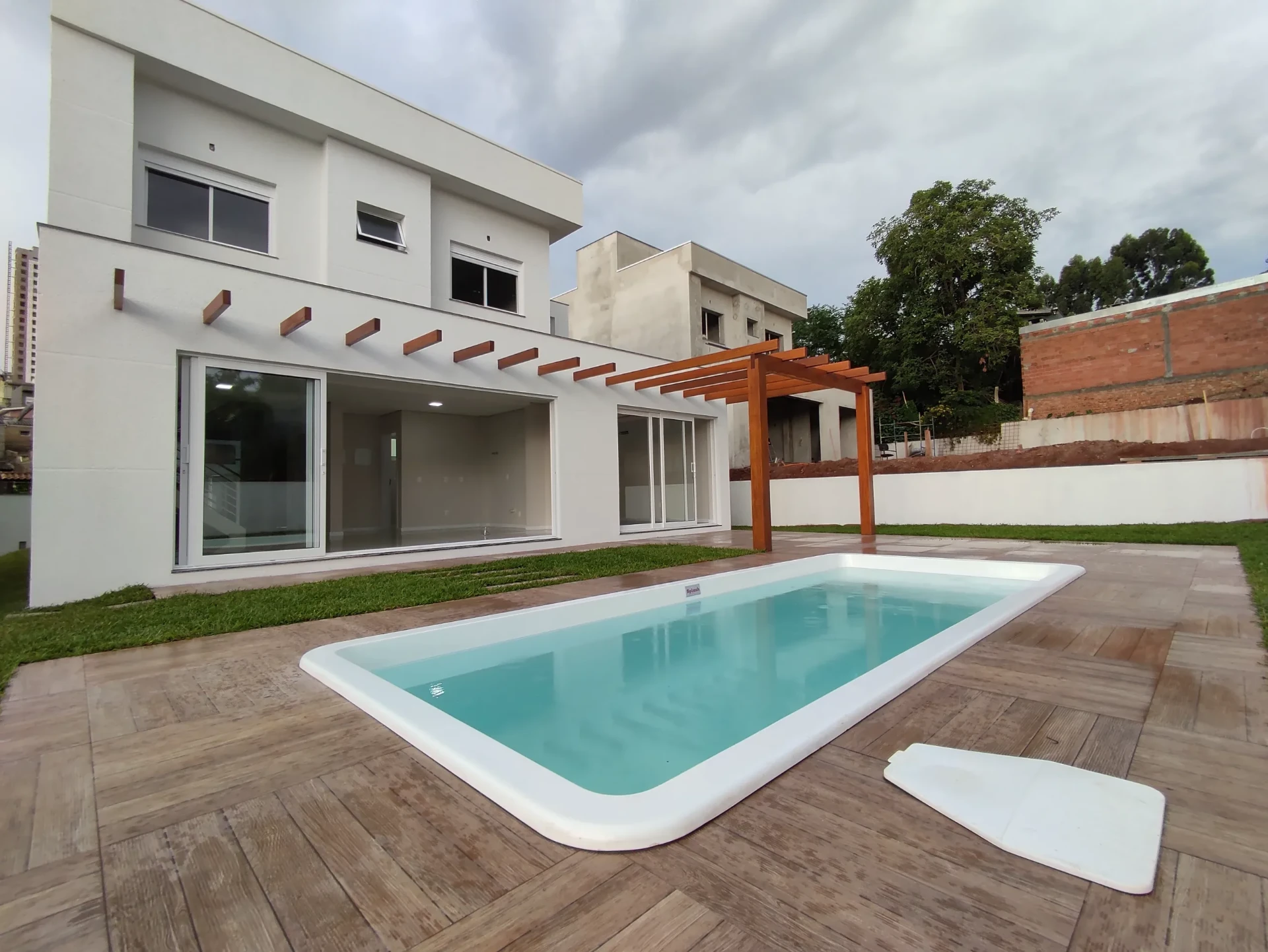 Área externa com piscina e pergolado de casa de alto padrão